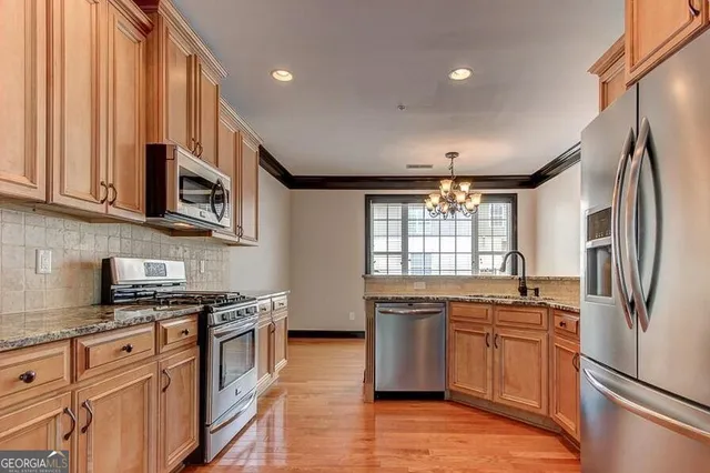 a kitchen with stainless steel appliances granite countertop a stove a sink and a refrigerator