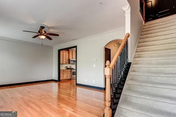 a view of an empty room with wooden floor and a ceiling fan