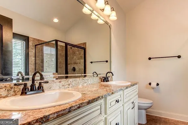a bathroom with a granite countertop sink a toilet and a mirror