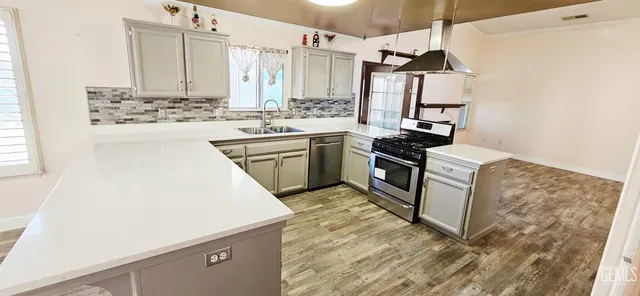 a kitchen with stainless steel appliances kitchen island granite countertop a stove a sink and a refrigerator