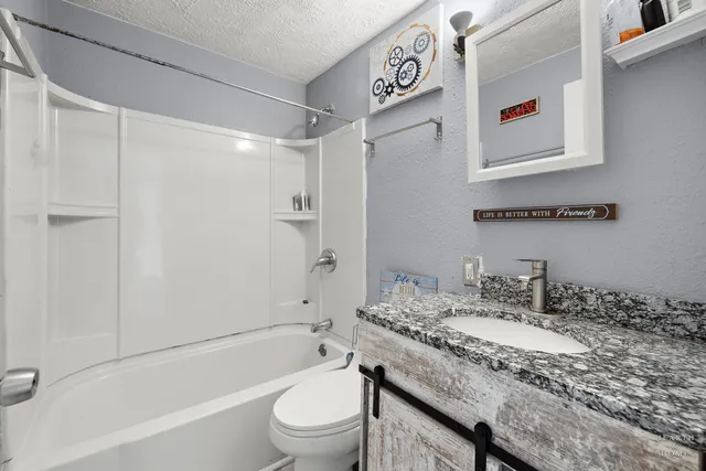 a bathroom with a granite countertop sink a toilet and shower