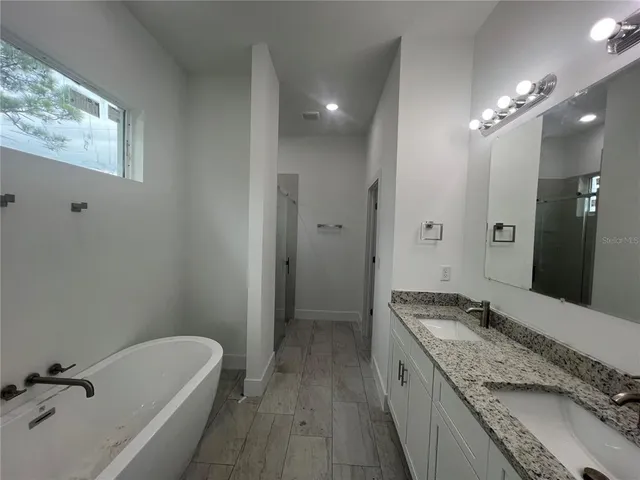 a spacious bathroom with a granite countertop tub sink and mirror
