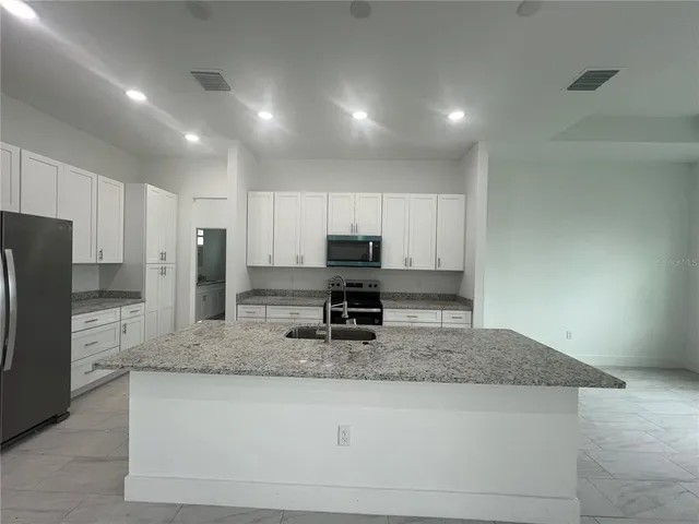 a kitchen with stainless steel appliances granite countertop a sink refrigerator and cabinets