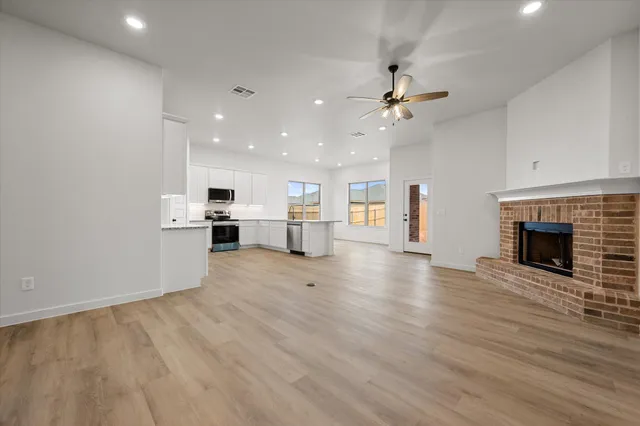 an empty room with kitchen fireplace and wooden floor