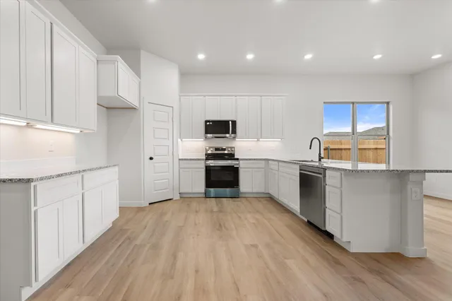 a kitchen with granite countertop white cabinets and stainless steel appliances