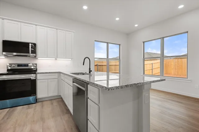 a kitchen with granite countertop a stove a sink and a microwave
