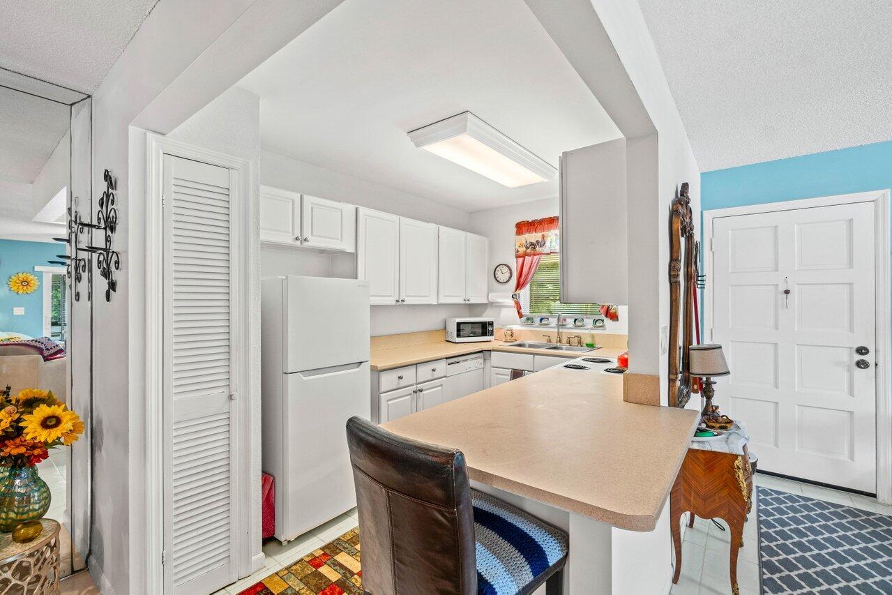 1124 Northwest 13th Street, Unit 204A Boca Raton, FL 33486 - Photo 6 of 30 a kitchen with a refrigerator a stove and a dining table with wooden floor