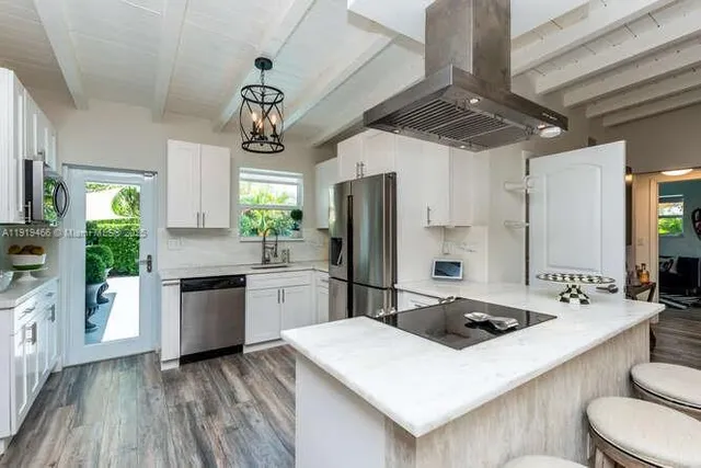 a kitchen with a center island wooden floor and stainless steel appliances