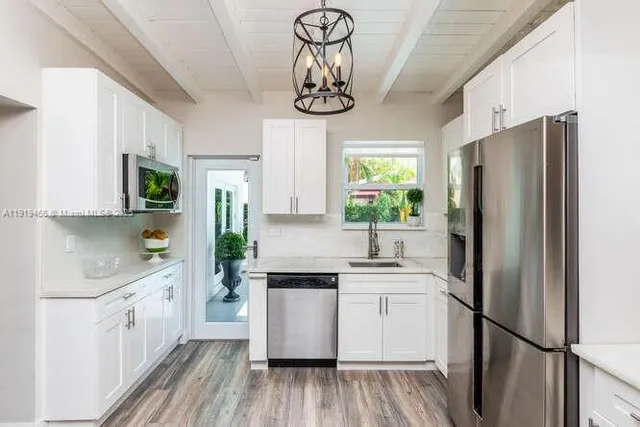 a kitchen with stainless steel appliances granite countertop a refrigerator a sink dishwasher a stove and white countertops with wooden floor