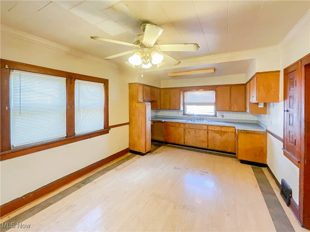 14703 Granger Road Maple Heights, OH 44137 - Photo 12 of 35 Kitchen with light wood-style flooring, brown cabinetry, ornamental molding, and ceiling fan