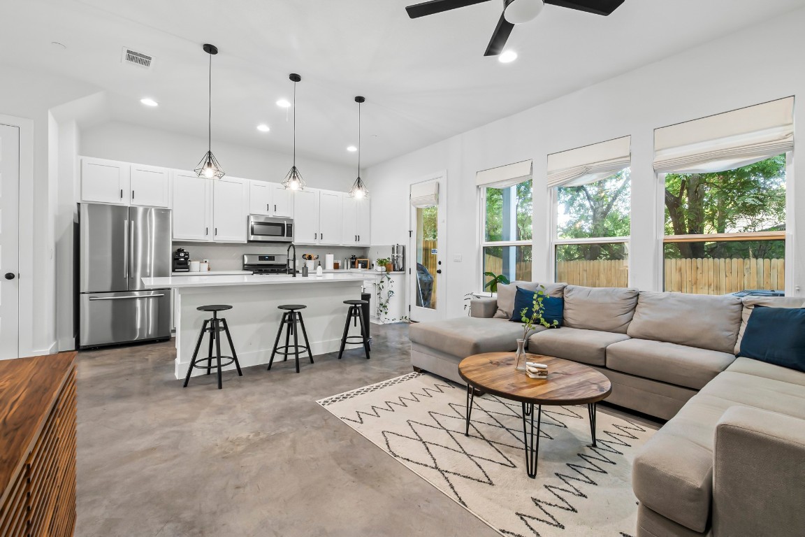 a living room with stainless steel appliances kitchen island furniture and a large window