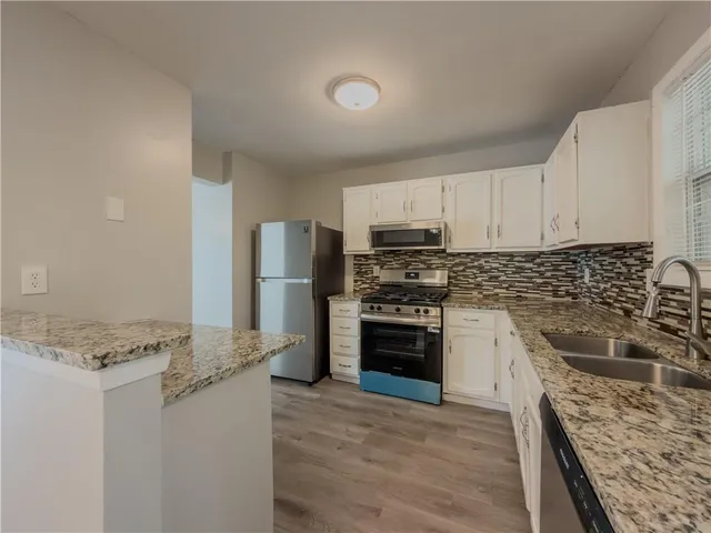 a kitchen with granite countertop a refrigerator stove and sink