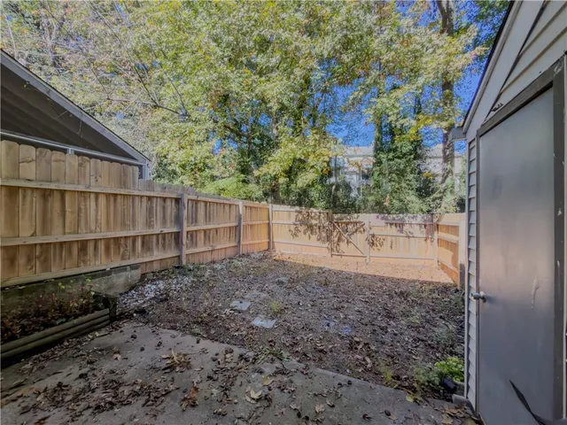 a view of a backyard with plants and large trees