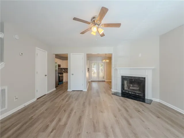 an empty room with wooden floor fireplace and windows