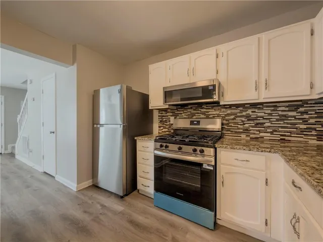 a kitchen with cabinets stainless steel appliances and wooden floor
