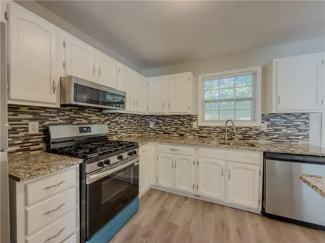 a kitchen with granite countertop a sink cabinets and stainless steel appliances