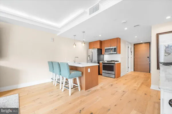 a kitchen with stainless steel appliances kitchen island granite countertop a table chairs microwave and sink
