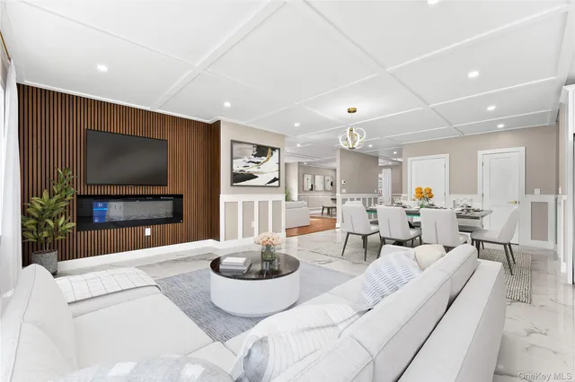 a living room with furniture a flat screen tv and kitchen view