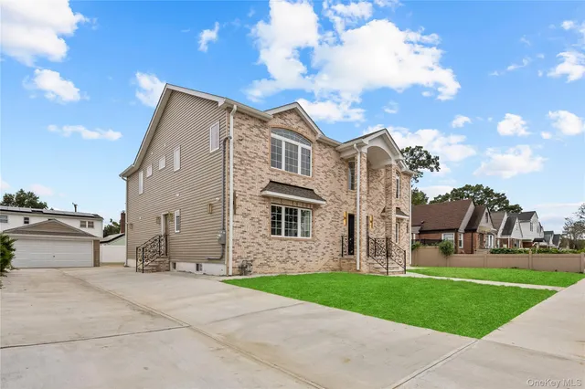a view of a white house next to a yard with big trees