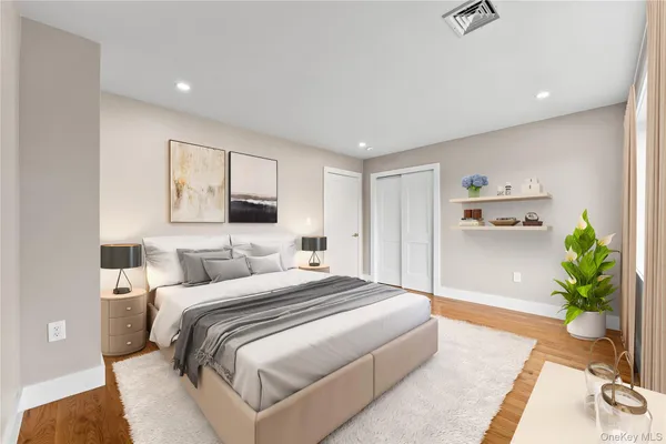 a bedroom with a large bed and potted plant with wooden floor