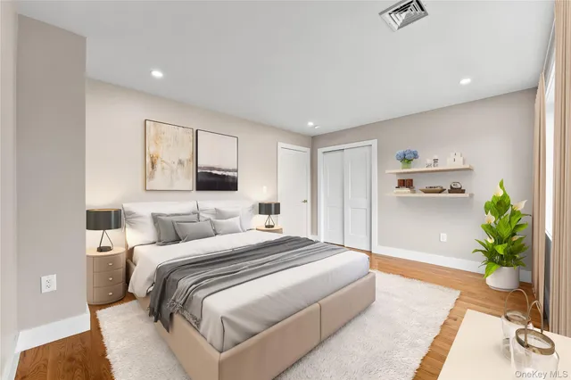 a bedroom with a large bed and potted plant with wooden floor