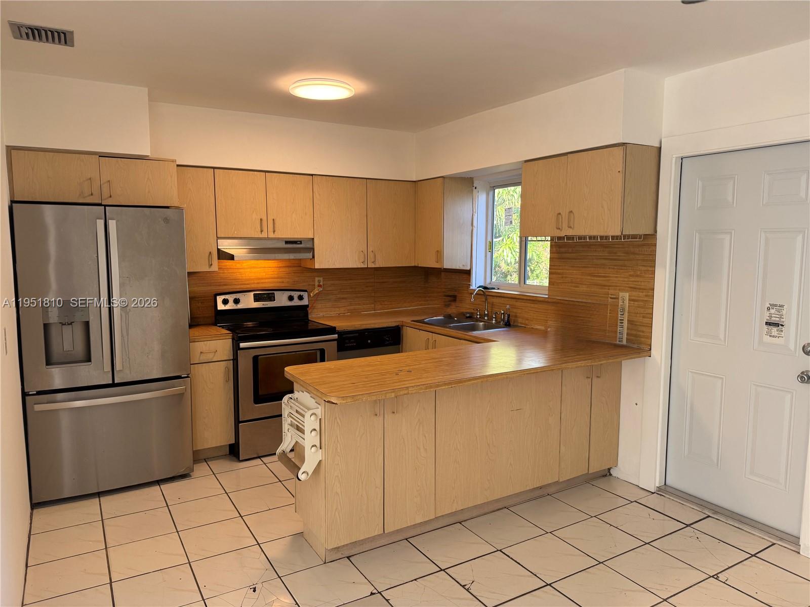 3535 Northwest 82nd Street Miami, FL 33147 - Photo 3 of 14 a kitchen with stainless steel appliances a refrigerator sink and microwave