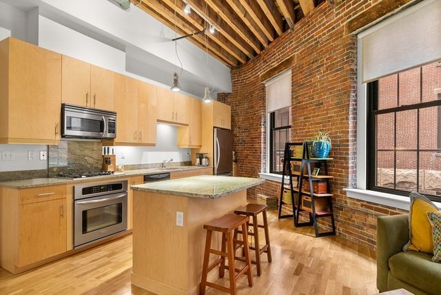 a kitchen with stainless steel appliances granite countertop a stove a sink dishwasher and a refrigerator with wooden floor