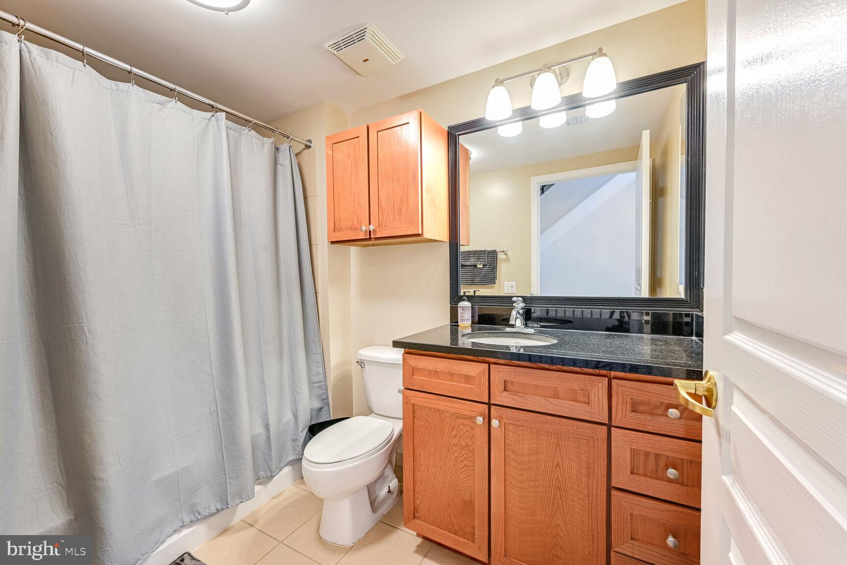 616 E Street Northwest, Unit 1150 Washington, DC 20004 - Photo 14 of 75 a bathroom with a granite countertop sink toilet and mirror