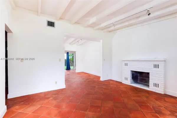 a view of an empty room with wooden floor and a fireplace