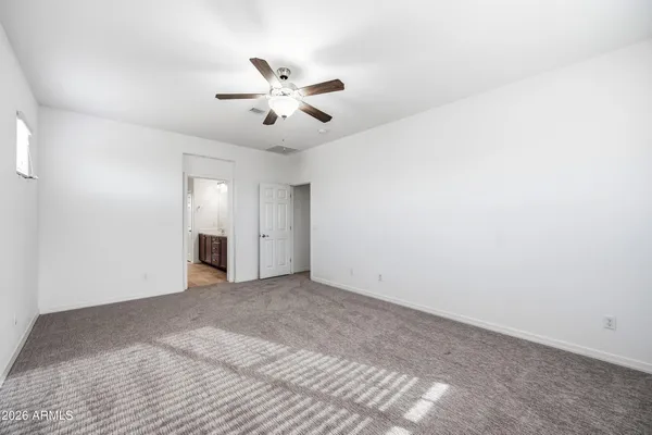 a view of an empty room with chandelier fan