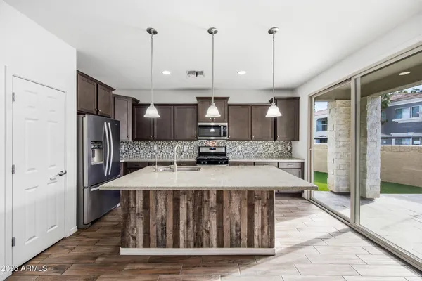 a large kitchen with stainless steel appliances kitchen island granite countertop a refrigerator a stove a sink with a island and chairs