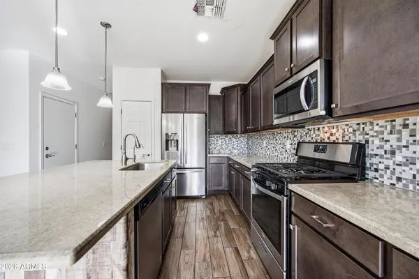 a kitchen with stainless steel appliances granite countertop a sink a stove and a refrigerator