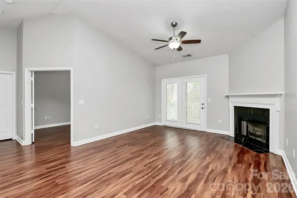 a view of an empty room with wooden floor fireplace and a window