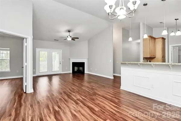 a view of a hallway with wooden floor and a kitchen