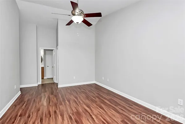 a view of room with hardwood floor and a ceiling fan