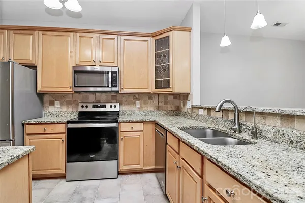 a kitchen with stainless steel appliances granite countertop a sink stove microwave and refrigerator