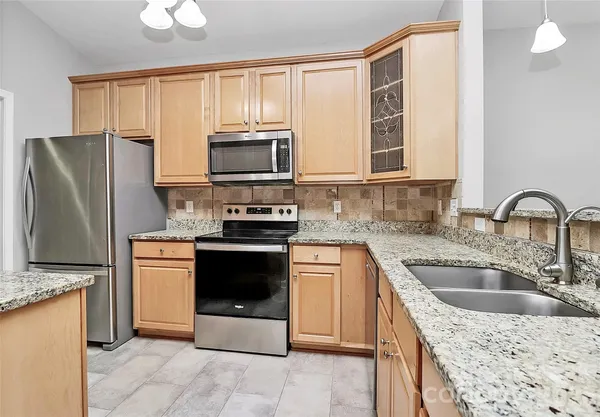 a kitchen with granite countertop a refrigerator stove and sink