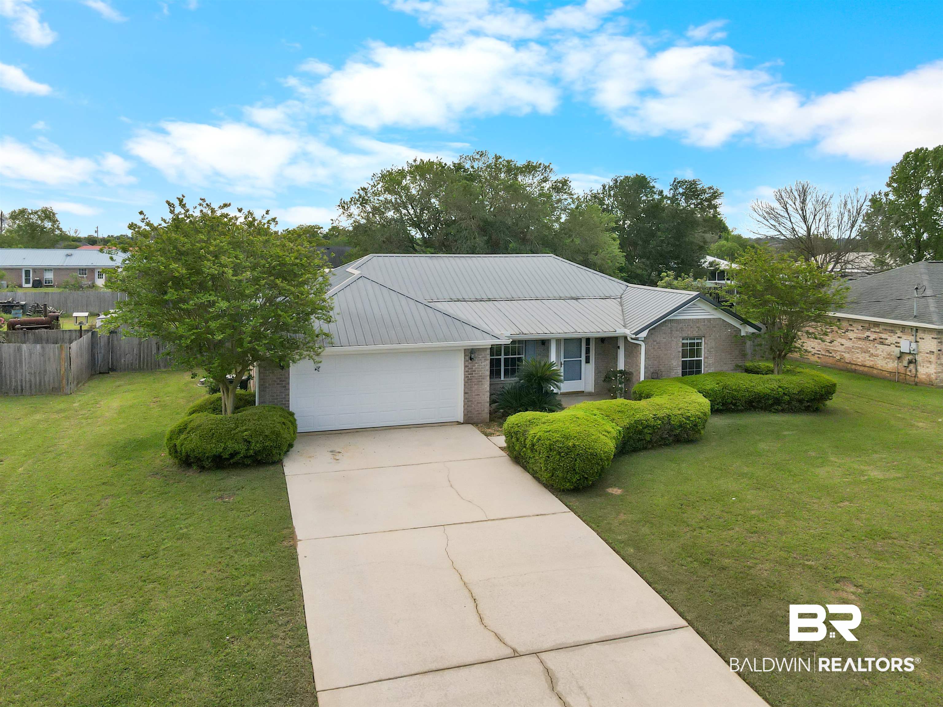 8940 Caitlin Street Foley, AL 36535 - Photo 17 of 27 Ranch-style home featuring brick siding, a garage, driveway, and a metal roof