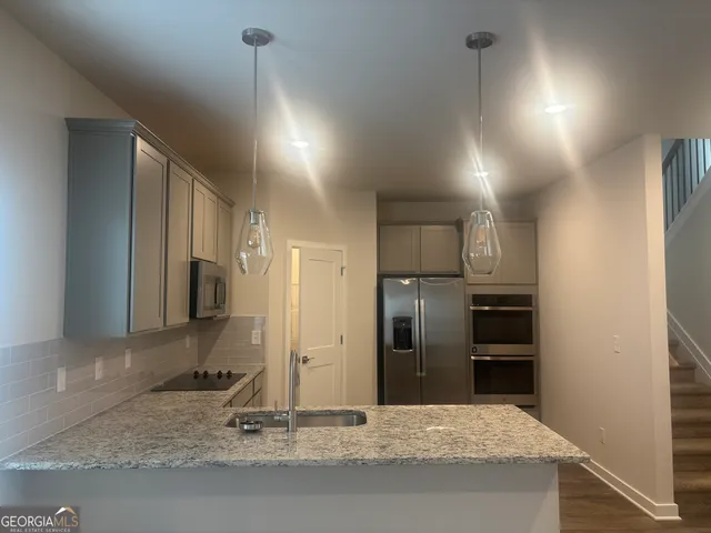 a kitchen with stainless steel appliances kitchen island granite countertop a refrigerator and a sink