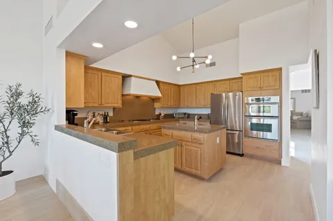 a kitchen with stainless steel appliances granite countertop a sink a stove a refrigerator cabinets and living room view