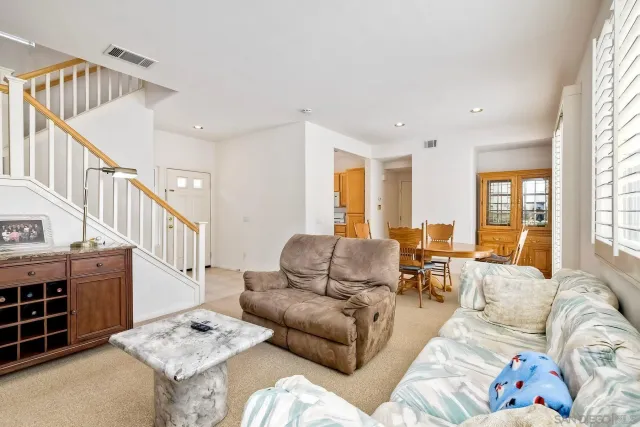 a living room with furniture and a dining table next to a window