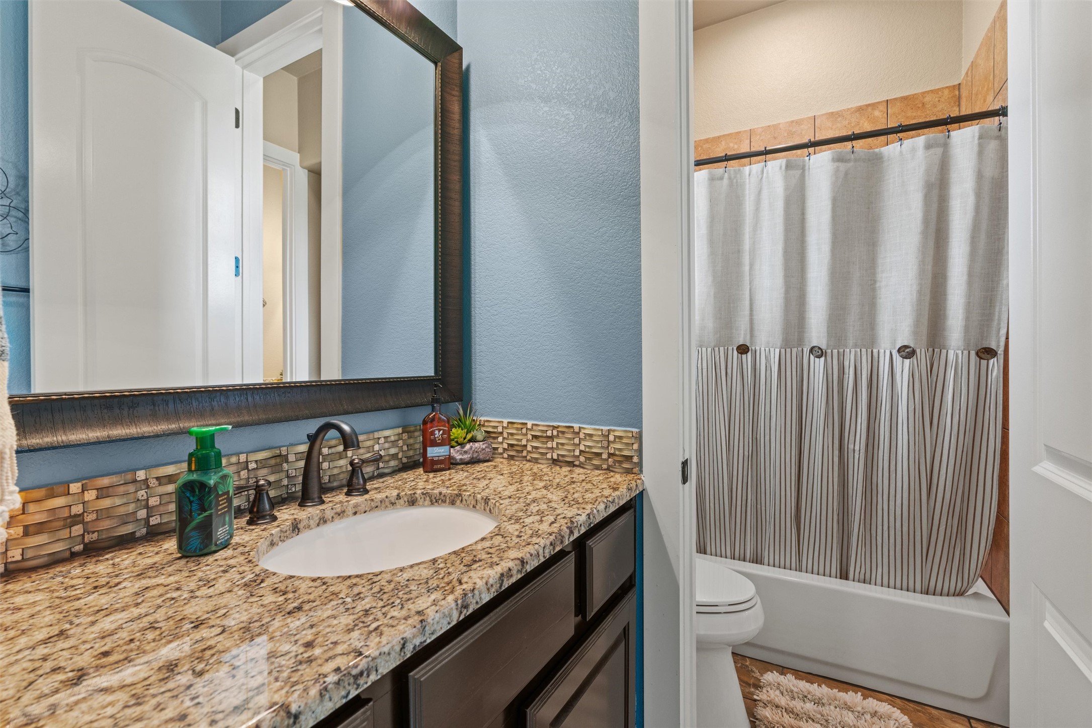 104 Adobe Cove Georgetown, TX 78633 - Photo 23 of 40 A well-appointed bath features a rich granite vanity and a tub with tiled surround.
