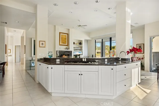 a kitchen with granite countertop white cabinets white appliances a sink and a large window