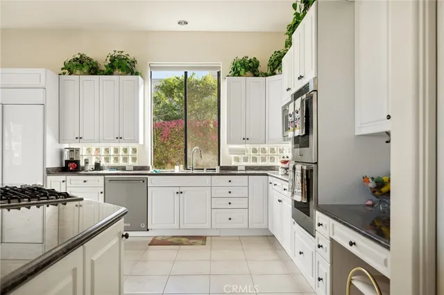 a kitchen with stainless steel appliances granite countertop a sink and dishwasher with white cabinets