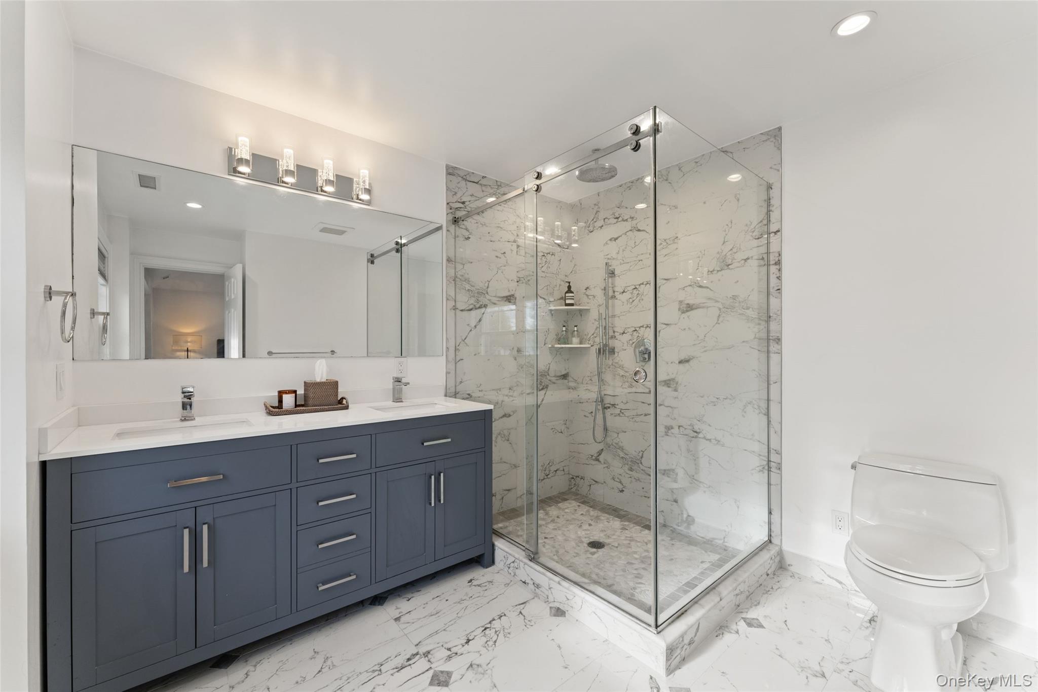 109 Lee Road Scarsdale, NY 10583 - Photo 18 of 33 Bathroom with double vanity, light marble finish flooring, a marble finish shower with frameless shower door