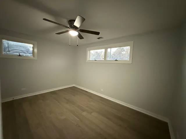 an empty room with wooden floor and ceiling fan