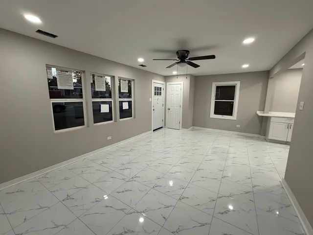 a view of an empty room with window and chandelier