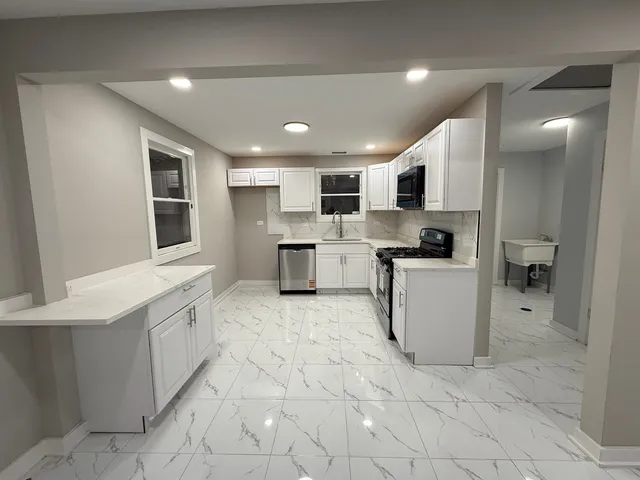 a large kitchen with stainless steel appliances granite countertop a sink and cabinets