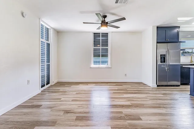 a view of an empty room with a window and wooden floor