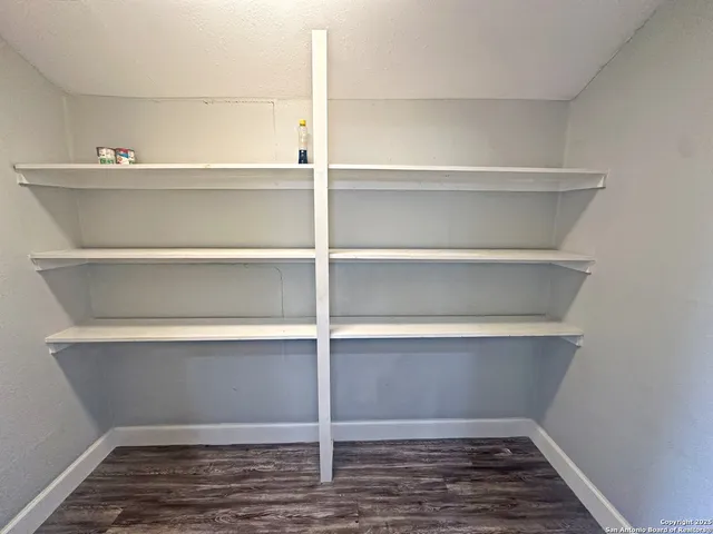 an empty room with wooden floor cabinet and windows